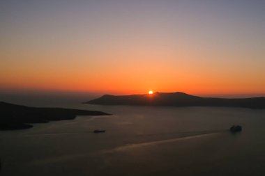 Spectacular sunset view and a ferry boat leaving the port of Athinios in Fira Santorini
