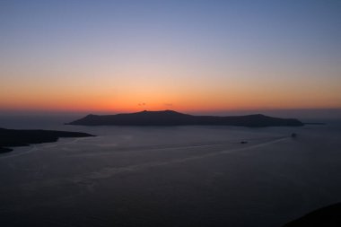 Fira Santorini 'nin çatılarından muhteşem bir gün batımı manzarası.