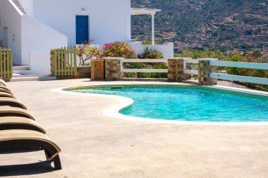 Ios, Yunanistan - 15 Eylül 2022: Yunanistan 'ın popüler Mylopotas plajında yüzme havuzu ve güneş yatağı manzarası