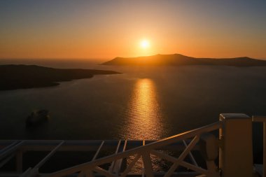 Fira Santorini 'nin çatılarından muhteşem bir gün batımı manzarası.
