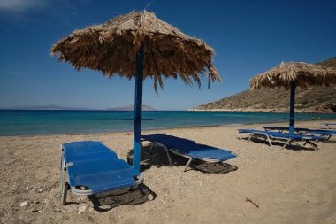 Sun beds and a sun umbrellas at the amazing beach of Agia Theodoti in Ios Greece