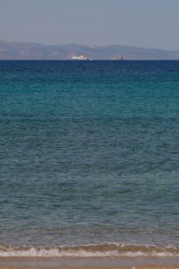 Ios, Greece - June 6, 2021 : View of the beautiful beach of Agia Theodoti and a Ferry boat in the distance