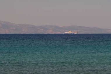 Ios, Greece - June 6, 2021 : View of the beautiful beach of Agia Theodoti and a Ferry boat in the distance