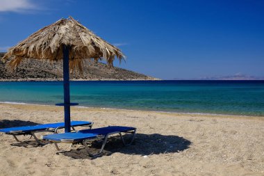 Two sun beds and a sun umbrella at the amazing beach of Agia Theodoti in Ios Greece