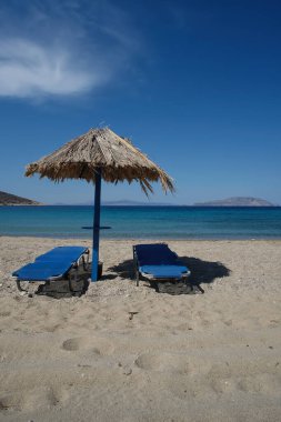 Two sun beds and a sun umbrella at the amazing beach of Agia Theodoti in Ios Greece