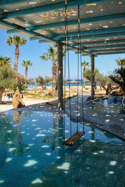 Ios, Greece - June 6, 2021 : A beautiful decorated swimming pool with a swing at a luxury tourist resort in Ios Greece