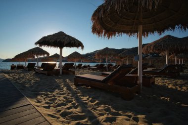 Ios, Yunanistan - 3 Haziran 2021: Yunanistan 'daki ünlü Mylopotas plajında lüks güneş yatakları ve güneş şemsiyeleri manzarası 