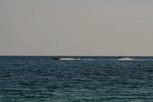 stock image Ios, Greece : May 30, 2021 : Tourists being dragged across the sea by a boat on a jet ski at the famous Mylopotas Beach in Ios Greece