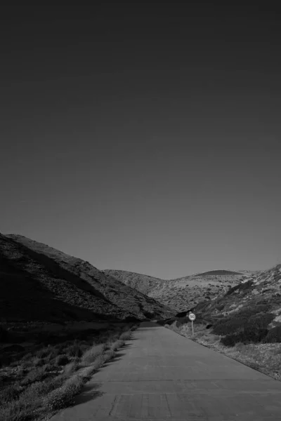 希腊爱荷斯岛上一条空旷的道路和一个黑白相间的限速标志 — 图库照片