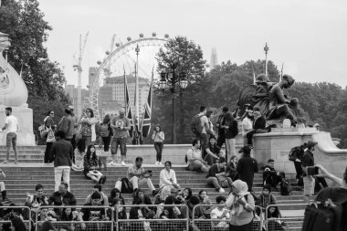 Londra, Birleşik Krallık - 23 Mayıs 2018: Kraliçe Victoria Anıtı 'nda turistlerin manzarası ve arka planda siyah-beyaz Londra Gözü