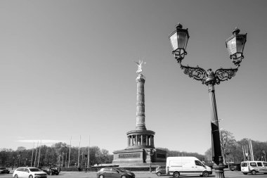 Berlin, Almanya - 19 Nisan 2023: Berlin Almanya 'daki güzel Zafer Sütunu, arabalar ve Berlin Almanya' da siyah beyaz bir sokak lambası