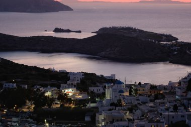 Güneş çarpıcı bir şekilde batarken, Yunanistan 'ın liman ve Ios köyünün panoramik manzarası