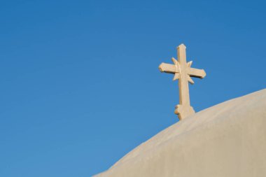 Yunanistan 'daki bir ortodoks beyazlatılmış kilisesinin tepesinde bir haç ve arka planda mavi bir gökyüzü. 