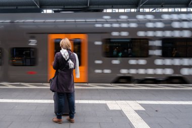 Bonn Almanya 'nın merkez tren istasyonunda duran bekar bir kadın ve platformdan ayrılan bir tren görülüyor.