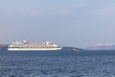 Santorini, Yunanistan - 7 Eylül 2023: Santorini 'nin nefes kesici volkanik manzarasının yanında büyük bir yolcu gemisine bakmak