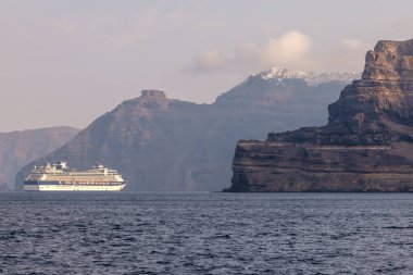 Santorini, Yunanistan - 7 Eylül 2023: Santorini 'nin nefes kesici volkanik manzarasının yanında büyük bir yolcu gemisine bakmak