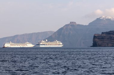 Santorini, Yunanistan - 7 Eylül 2023: Santorini 'nin nefes kesici volkanik manzarasının yanındaki iki büyük yolcu gemisinin görüntüsü