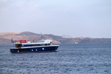 Santorini, Yunanistan - 7 Eylül 2023: Santorini Yunanistan 'da küçük bir tekne gezisi ve arka plandaki yanardağ