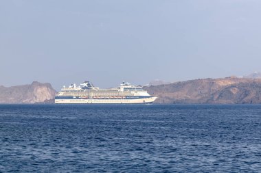 Santorini, Yunanistan - 7 Eylül 2023: Santorini 'nin nefes kesici volkanik manzarasının yanında büyük bir yolcu gemisine bakmak