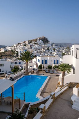 Ios, Yunanistan - 8 Eylül 2023: Arka planda Yunanistan 'ın beyazlatılmış köyü ve yüzme havuzlu pitoresk bir otel manzarası