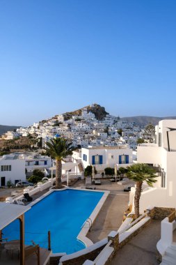 Ios, Yunanistan - 9 Eylül 2023: Arka planda Yunanistan 'ın beyazlatılmış köyü ve yüzme havuzlu pitoresk bir otel manzarası