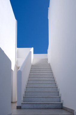 View of a whitewashed buildings steps leading upstairs and a blue sky in Ios Greece