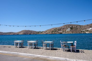 Restoran sandalyeleri, masalar, dekorasyon ışıkları ve Yunanistan 'ın arka planında mavi deniz manzarası