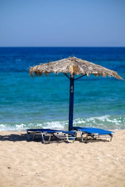 Yunanistan 'daki muhteşem Agia Theodoti plajında iki güneş yatağı ve bir güneş şemsiyesi manzarası