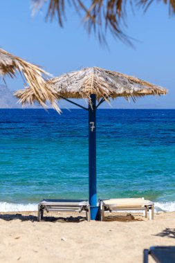 Yunanistan 'daki muhteşem Agia Theodoti plajında iki güneş yatağı ve bir güneş şemsiyesi manzarası