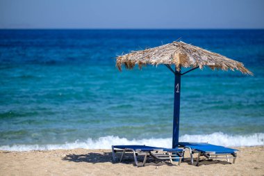 Yunanistan 'daki muhteşem Agia Theodoti plajında iki güneş yatağı ve bir güneş şemsiyesi manzarası