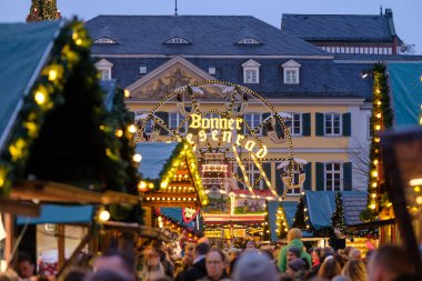 Bonn, Almanya - 16 Aralık 2023: Bonn Almanya 'da geleneksel ve resimli Noel Pazarı ve arka planda bir dönme dolap etrafında yürüyen kalabalığın görüntüsü
