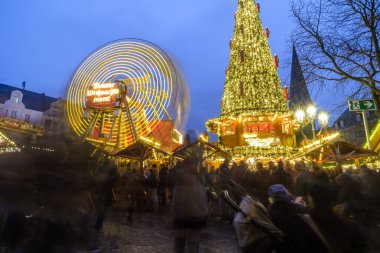 Bonn, Almanya - 16 Aralık 2023: Bonn Almanya 'daki Noel pazarında aydınlatılmış bir Noel ağacı ve dönme dolap manzarası