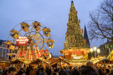 Bonn, Almanya - 16 Aralık 2023: Bonn Almanya 'daki Noel pazarında aydınlatılmış bir Noel ağacı ve dönme dolap manzarası