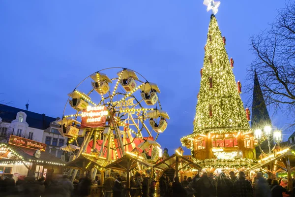 Bonn, Almanya - 16 Aralık 2023: Bonn Almanya 'daki Noel pazarında aydınlatılmış bir Noel ağacı ve dönme dolap manzarası