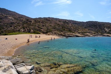 Ios, Yunanistan - 15 Eylül 2023: Ios 'taki Pikri Nero' nun kumlu ve turkuaz plajının tadını çıkaran genç turistleri görmek