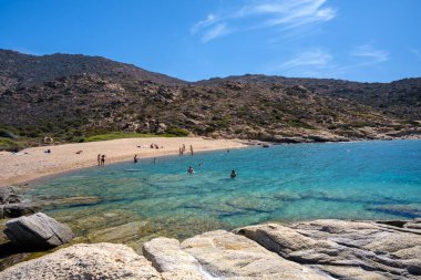 Ios, Yunanistan - 15 Eylül 2023: Ios 'taki Pikri Nero' nun kumlu ve turkuaz plajının tadını çıkaran genç turistleri görmek