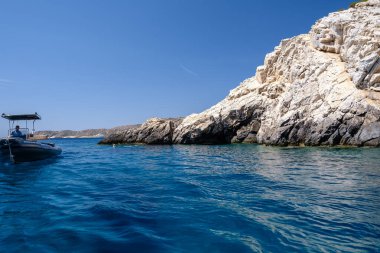 Ios, Yunanistan - 15 Eylül 2023: Yunanistan 'da şnorkelle yüzmek için gizli bir mücevher olan Neverbay Cliffs' in yanındaki turistik gezi teknesinin görüntüsü