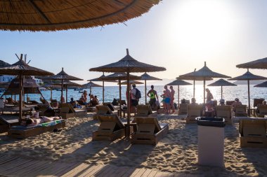 Ios, Yunanistan - 16 Eylül 2023: Yunanistan 'daki Mylopotas' ın popüler ve güzel kumlu plajında güneş yatakları ve güneş şemsiyelerinin manzarası