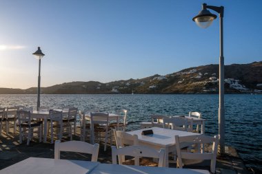 Yunanistan 'da arka planda beyaz sandalyeler, masalar ve mavi deniz manzarası