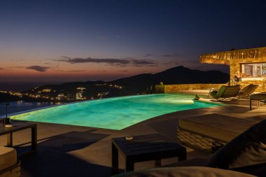 Ios, Yunanistan - 17 Eylül 2023: Yunanistan 'da bir salon barında yüzme havuzu ve büyülü bir günbatımı manzarası