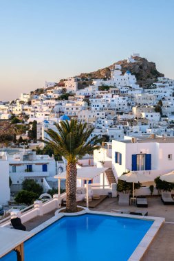 Ios, Yunanistan - 12 Eylül 2023: Yunanistan 'ın Ios kentinde yüzme havuzu ve beyazlatılmış Ios köyü bulunan pitoresk bir otel manzarası
