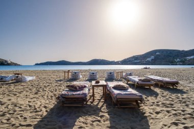 Ios, Yunanistan - 2 Mayıs 2024: Yunanistan 'ın Ios kentindeki güzel Gialos plajında güneş yatakları, plaj koltukları ve masaların manzarası