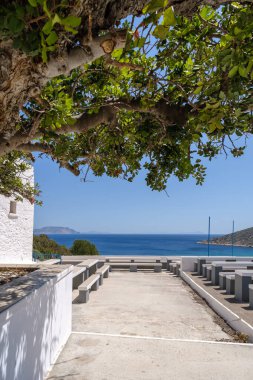 Yunanistan 'ın en güzel turkuaz plajına bakan Agia Theodoti kilisesindeki bank ve masaların manzarası