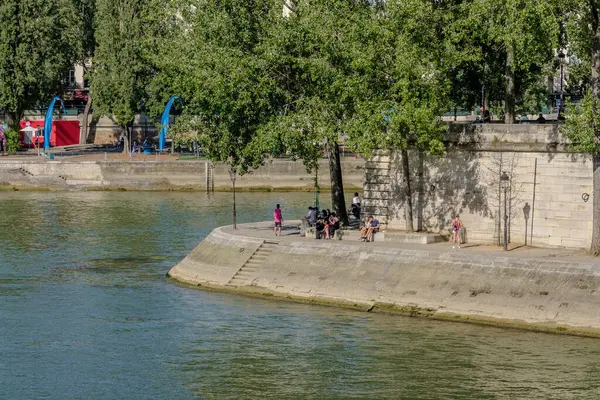 Paris, Fransa - 10 Ağustos 2024: Louis Aragon Meydanı 'nda oturan ve Seine nehrinin tadını çıkaran insanların görüntüsü
