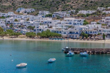 Sifnos Yunanistan 'ın pitoresk limanındaki çeşitli balıkçı teknelerinin manzarası ve arka planda güzel bir kumsal