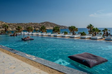 Ios, Yunanistan - 6 Eylül 2024: Yunanistan 'daki Koumbara plajına bakan inanılmaz bir açık yüzme havuzu manzarası