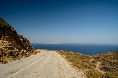 Yunanistan 'ın arka planında ıssız bir yol ve Ege Denizi manzarası