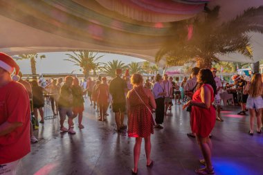 Ios, Yunanistan - 4 Eylül 2024: Yunanistan 'daki sahil kulübündeki geleneksel Noel Partisi' nde kutlama, içme ve dans eden mutlu turistleri görmek