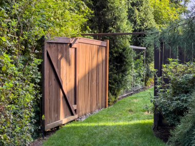 Güneşli bir günde yemyeşil bir arka bahçeye açılan açık ahşap bir kapının güzel manzarası.