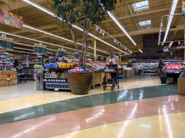 Snohomish, WA USA - circa November 2022: Wide view of people shopping in the produce section of a Haggen grocery store. clipart